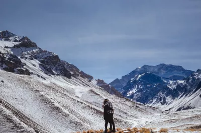 Recargue Sus Baterías Durante Un Viaje A Argentina : Dos personas abrazándose a pie de la montaña nevada del Aconcagua
