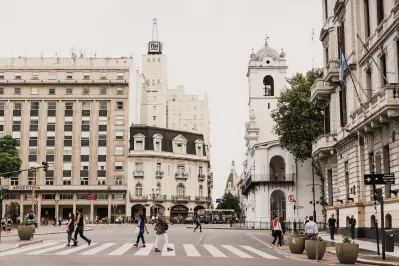 Recargue Sus Baterías Durante Un Viaje A Argentina : Mujer cruzando la calle peatonal entre edificios altos en Argentina