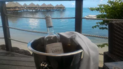 ¿Cuáles son los mejores bungalows de lujo sobre el agua en los centros turísticos de la Polinesia Francesa? : Botella de vino con vista a los bungalows sobre el agua de Tahití.