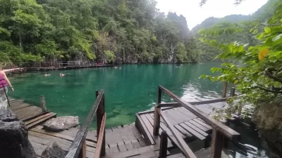 Mini Viagem Guia: Um dia de aventura em Coron, Palawan : As águas cristalinas do lago Kayangan, com uma passarela de madeira que leva a um ponto de vista impressionante.