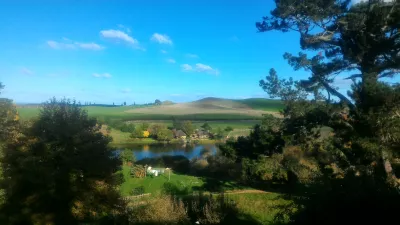 Hobbiton movie set tour, a visit of the hobbit village in New Zealand : View on the Green Dragon inn from the top of the hill