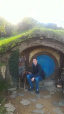 Hobbiton movie set tour, a visit of the hobbit village in New Zealand : In front of a Hobbit house with a blue door
