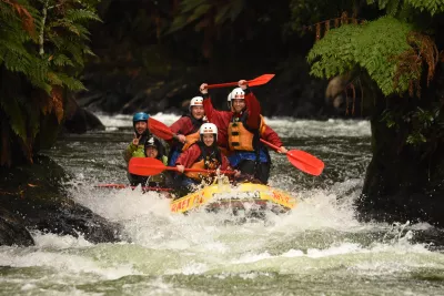 Extreme white water rafting in Rotorua, New Zealand: down a 7 meters waterfall! : Standing on the raft on rapids